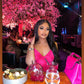 a woman sitting at a table with pink flowers
